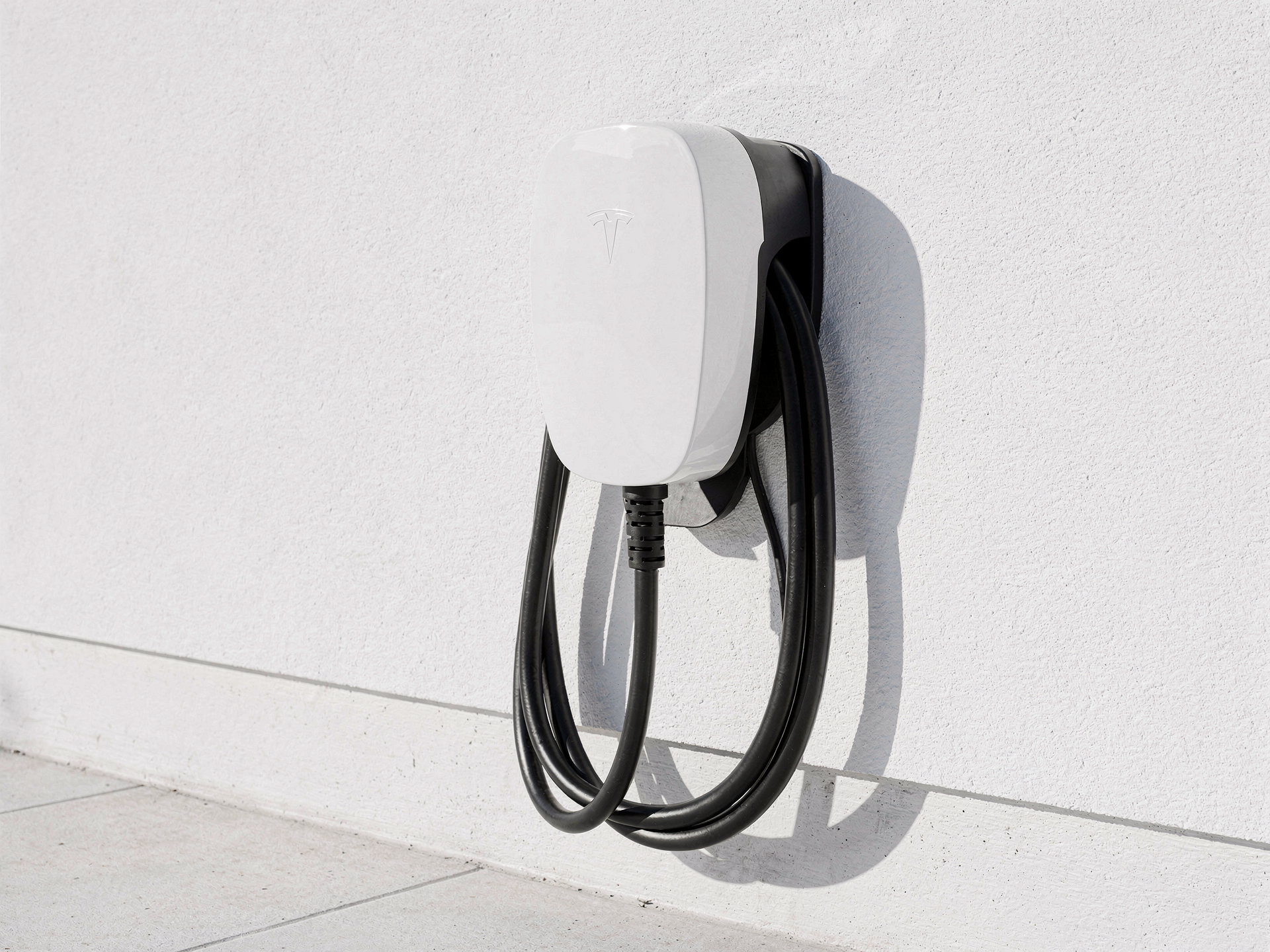 A sleek white EV wall connector freshly installed on a bright clean garage wall